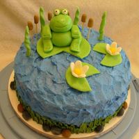 Frog And Lilypad Cake Buttercream icing for water and grass around bottom. Rocks, cattails, and flowers are gumpaste. Frog and lilypads are a mixture of MMF and...