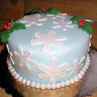Christmas Cake 8 inch round cake covered in light blue Satin Ice fondant. Dusted cake with white luster dust. Snowflakes and pearls are fondant and holly...
