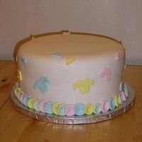 Cute As A Button Choc. cake with Choc. frosting. Cake is covered in Satin Ice. Baby clothes and Buttons also made from Satin Ice.