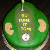 Golf Retirement Cake Cake covered in fondant with fondant accents. Graham cracker crumbs used for the sand traps. Lollipop stick for the flag.