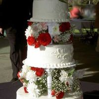 Red Roses For Jordan tiered cake with roses and other red flowers between layers and fleur de lis style scroll work on sides.
