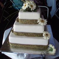 Flax And Gerbera Wedding Cake fruit cakes with almond and fondant. Wrapped with woven flax ribbon and decorated with fresh gerberas