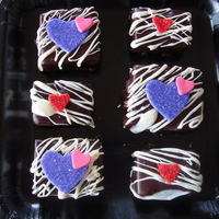 Valentine's Day Brownies Valentine's Day brownies coated in ganache, white chocolate drizzle, fondant accents.