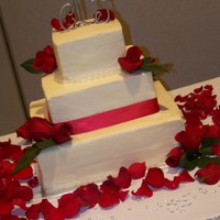 Simply Red And White vanilla cake with buttercream. Satin ribbon, fresh flowers, and strands of pearls. For a simple, elegant fall wedding.