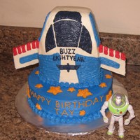 Buzz Lightyear Rocketship 10 inch round. 1/4 sheet cake cut to form rocketship. Wings made of cake board (greaseproof) and covered with frosting.