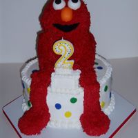 Elmo Carved Elmo done in pound cake covered in BC on 8 in. chocolate round covered in BC. Fondant eyes, nose, mouth, and dots on cake. Arms,...