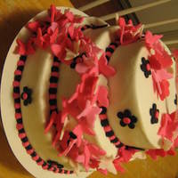 Pink Butterfly Parade 6"/8"/10" tiered covered in buttercream. All butterflies and flower are fondant, as is banner on top.