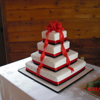 Red And Black Wedding Cake White Wedding cake covered in fondant with real ribbon at the base of each tier. Bow and streamers are fondant
