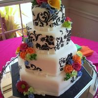 Black Damask With Bright Flowers This four tier hexagon cake was covered in homemade white chocolate fondant and then stenciled with black royal icing. The bright colored...