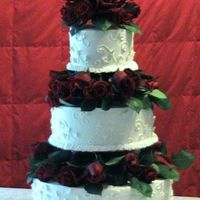 Wedding Cake With Roses This is the first wedding cake I did. It is three tiers with red roses seperating each, it was nerve racking.