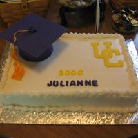 Graduation Cake 11x15 white cake with white buttercream icing. The graduation cap and UC emblem and letters are fondant. The tassle is made from cross-...