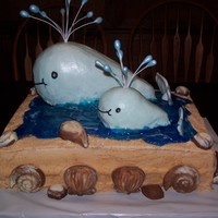 Mother And Baby Whale Buttercream icing on entire cake. White and milk chocolate shells. Crushed vanilla waffers to make the sand and piping gel for water. The...