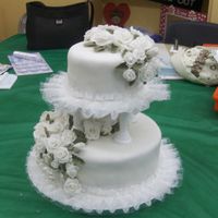 First Tiered Cake 10" & 6" with rolled fondant W/ fondant roses and leaves; no time for buttercream ruffle so bought one (also helped cover up...