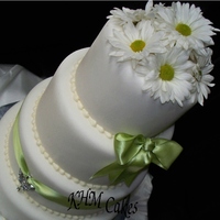 Butterfly Bling With Apple Green Ribbon on a 4 tier round stacked white cake covered in fondant with fresh daisies as the topper.