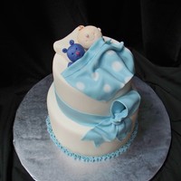 Baby Boy Baby Shower Cake with gumpaste baby, teddy bear, blanket, and fondant bow and ribbon.