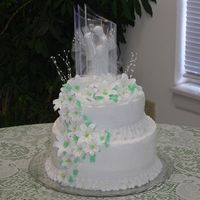 Wedding Cake W/lillies French vanilla cake w/buttercream icing. Lillies made from royal icing. Ribbon and shell border w/pearls. Reverse shells on top layer.