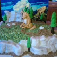 Alpha (From Alpha And Omega Movie) Cake Rocky bluffs are RKT covered in fondant and brushed with color dusts. Chocolate cake with SMB frosting. Alpha figure made of fondant.