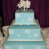 Snowflakes Blue butterceam iced square cakes, with piped on white buttercream snowflakes. Royal icing snowflakes on wires for a topper.