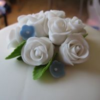 Flowers On Final Cake - Class Iii Here is a close-up of the fondant roses on top of the cake with some small blue fondant flowers sprinkled in. :)