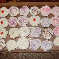 Strawberry Flavored Cupcakes strawberry cake with almond buttercream frosting and a variety of sprinkles/strawberry glaze & silver dragees for toppings.