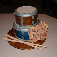 Two Tiered Drum Cake Set of two drums cake for a guys' birthday. Gumpaste drumsticks, and plaque. Cake is all fondant that was painted in different colors...