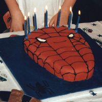 Spiderman Madeira cake cut into shape. Board covered with blue fondant and decorated with black fondant spider. Cake covered in red fondant and black...