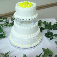 Mrs_Coras_83Rd_Birthday.jpg Buttercream frosting, with small yellow flowers on top tier. the names of all eleven children on bottom tier.