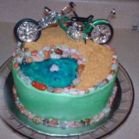 On Top Of The Hill This cake is an 8" round white cake with burrercream. The rocks are candy and the pond is tinted piping gel. The dirt road is made of...