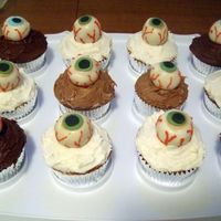 Buck-Eyeball Cupcakes Chocolate & Yellow Cupcakes topped with buckeye candy using white instead of dark chocolate and done up to look like eyeballs.