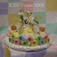 Baby Bootie With Gum Paste Flowers This is a baby Bootie filled with Gum Paste Flowers the board is a baby blanket done in patchwork cutters and the frig is done with...