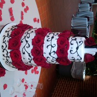 Black/white Wedding Cake 6-8-10-12 rounds covered in buttercream with black buttercream piping. Fresh red roses between the tiers.
