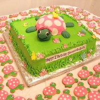 Turtle Cake Turtle cake with turtle cookies in the background. Baked the turtle shell in a pyrex bowl, arms and feet are fondant. Head is RKT covered...
