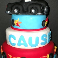 Hot Wheel Cake 3 tiered , red,white,blue, with flaming wheels and truck made of rice krispies and covered in fondant .