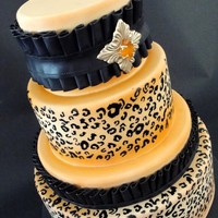 Leopard Print Display cake for wedding venue. The print is hand-painted and the ruffles are modeling chocolate. The "jewel" on the top tier is...
