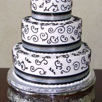 Brown Scrollwork And Ribbon 12/9/6 inch stacked rounds decorated with buttercream icing and satin ribbon.