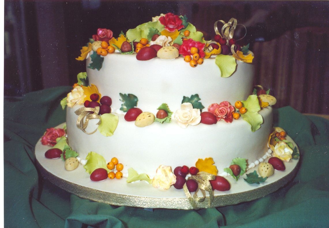 Harvest Thanksgiving 2 tier, fondant covered cake featuring gum paste almonds, pecans, hazelnuts, berries, fall leaves and roses.
