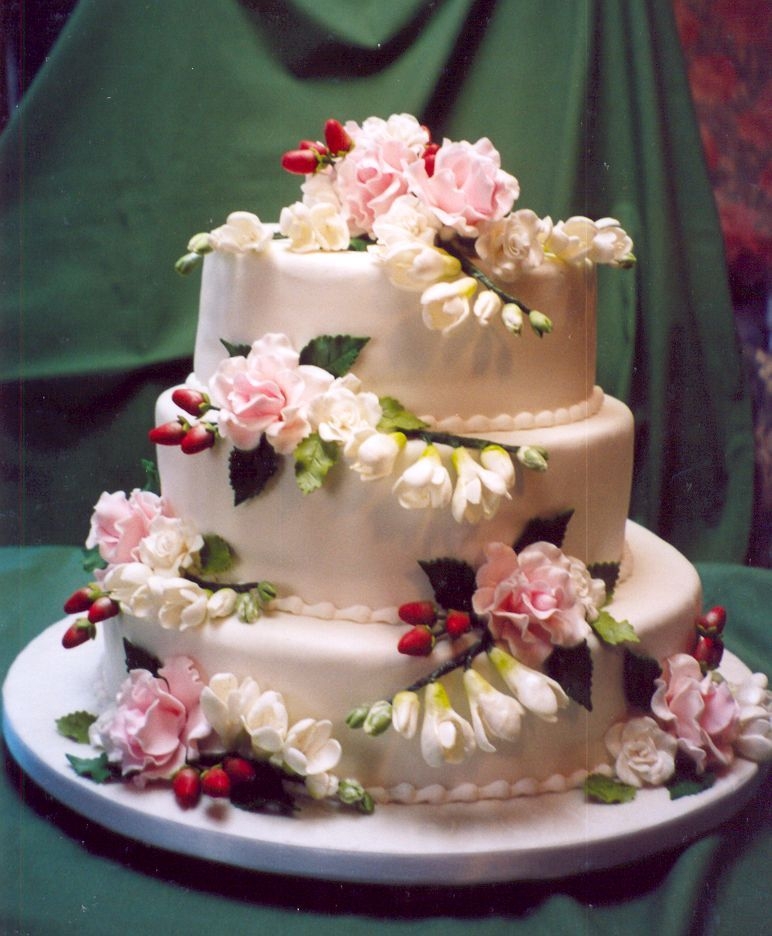 True Romance 3 tier, fondant covered, truly romantic wedding cake. Gum paste pink cabbage roses, white sweetheart roses, white freesia and red/green...