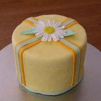 Daisy Cake 6 inch cake with fondant and gumpaste accents. The green ribbon is real. The fondant looks mottled (but isn't) because there is frost...