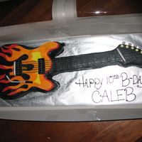 Flaming Guitar Cake cake pieced together in the shape of a guitar then covered in buttercream with fondont accents. designed own template for the flames. made...