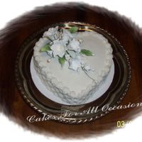 White Lily Cake Heart shaped cake decorated with white lily spray , basketweave on the sides, reverse shall border.