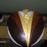 Tuxedo Triple chocolate. Chc. cake, chc. b/c, bathed w/ chc. ganache. Fondant accents w/ gold luster. This is the after pic. 10' heart pan