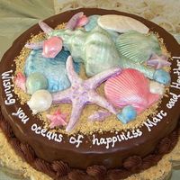 Oceans Of Happiness Bridal Shower Cake 12 inch round cake in chocolate ganache, covered in crushed graham crackers to resemble sand and hand poured white chocolate mint seashells...