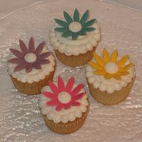 Flower Cupcakes White cake with BC frosting. We used the newer Wilton daisy cutouts. We made the flowers from fondant and dried them on upside-down egg...