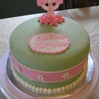 Mk Baptism 8in round covered in MFF with fondant and buttercream accents, and gumpaste flowers and cross. The fondant ribbon in the center of the cake...