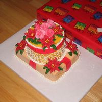Christmas Present Cake 9x13 with 2-9" rounds. Wrapped in fondant and topped with royal icing roses and poinsettias.