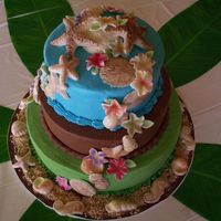 Seashell And Flowers Cascade Three tier cake (middle tier is chocolate, top and bottom are almond flavored) with a cascade of white chocolate seashells and bright...