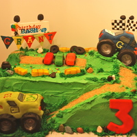 Monster Truck Bash Birthday Cake RK fondant covered monster trucks. One jumping off a ramp over 3 mini cars. Hay bales old tires, banners and all cars are handmade and...