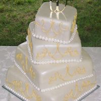 Ivory, Gold, & Pearl Wedding Cake The cake is covered in fondant and sprayed with a peart lustre dust. The gold piping is a design from the wedding dress.