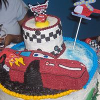 Dylans 3Rd Birthday Cars Cake 1 layer 18in w/2 layer 16in stacked w/ lightening mcqueen on top next to checkered tower cake.