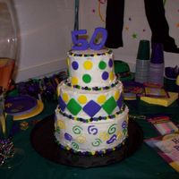 Mardi Gras Themed 50Th Birthday Party This is my first cake . it is a yellow cake covered in butter cream and the pieces are fondant. the beads going around the tiers are...